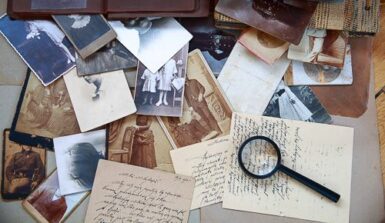 Archives photos et lettres manuscrites posées sur une table avec une loupe