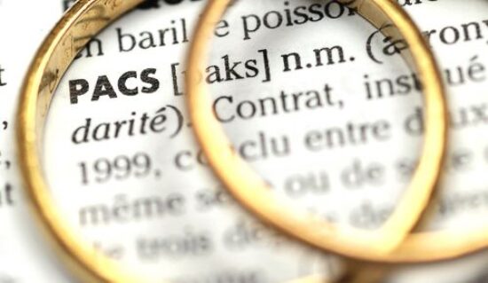 Définition du mot PACS dans un dictionnaire avec des anneaux de fiançailles posés dessus