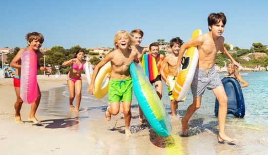 Jeunes enfants courant sur une plage avec des accessoires gonflables
