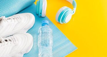 Paire de baskets, casque audio, et bouteille d'eau posés sur un tapis