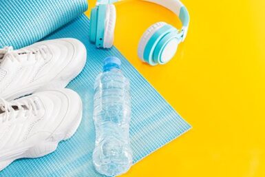 Paire de baskets, casque audio, et bouteille d'eau posés sur un tapis