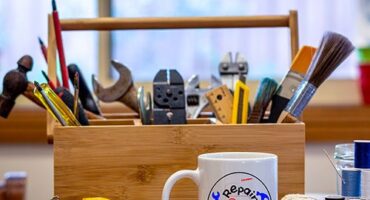 Mug repair cafe posé devant une boite à outils